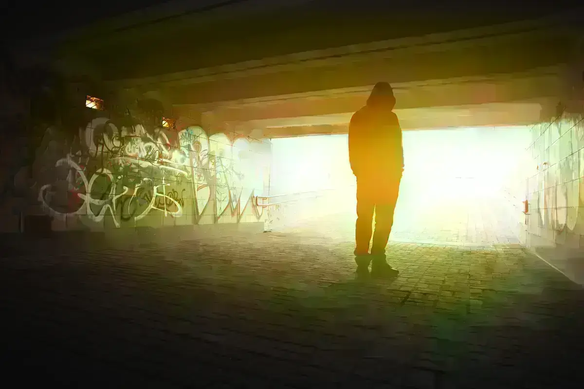Depressed person stands under a bridge.